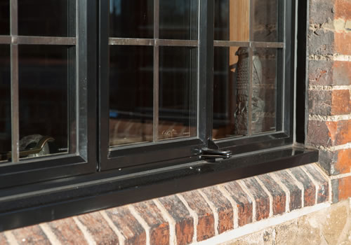Close exterior view of a metal window set within the brickwork