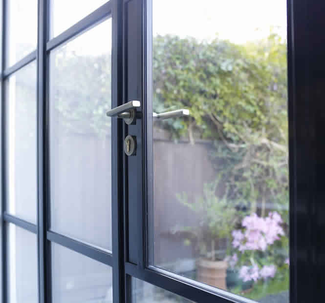 Close view of the black metal doors and brushed brass fittings